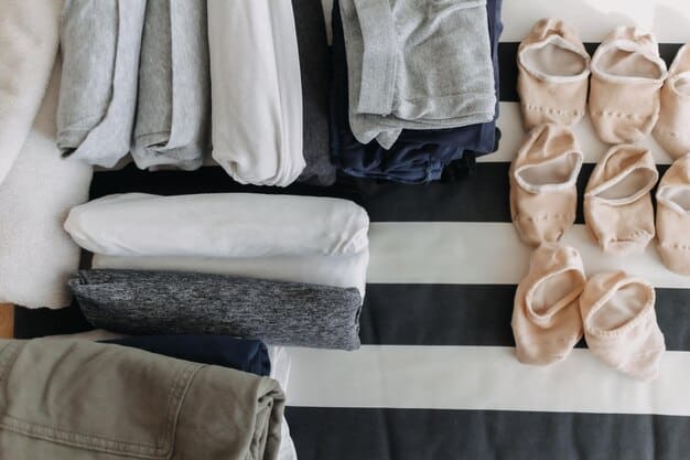 Close-up of a neatly organized capsule wardrobe showcasing ten essential clothing items including a white button-down shirt, a black blazer, a pair of dark wash jeans, a versatile knit sweater, a classic little black dress, neutral colored t-shirts, a pencil skirt and a trench coat.