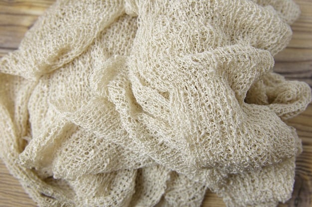 Close-up shot of various sustainable fabrics (organic cotton, recycled polyester, hemp) showing the texture and natural colors, arranged in an aesthetically pleasing manner on a wooden table.