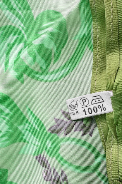 Close-up of a garment label displaying certifications such as GOTS (Global Organic Textile Standard) and Fair Trade, along with detailed information about the fabric composition (e.g., 100% organic cotton) and origin. The label is attached to a simple, well-made article of clothing.
