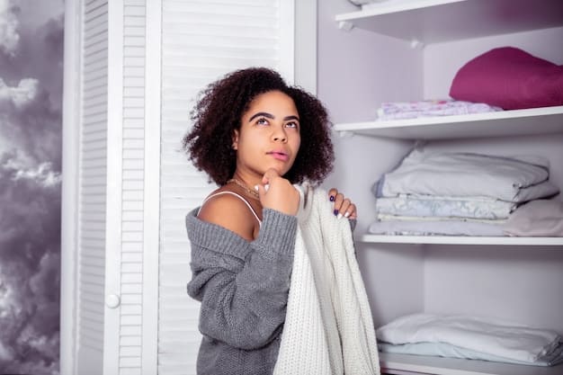 A person thoughtfully sorting through clothing in their closet, holding up a shirt to consider whether to keep, donate, or discard it, with piles of clothes sorted into different categories around them.