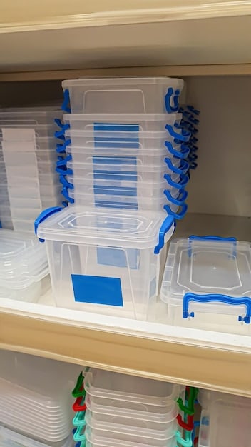 A set of clear plastic storage bins neatly stacked on a closet shelf, each labeled and containing folded clothes, illustrating efficient and transparent organization.