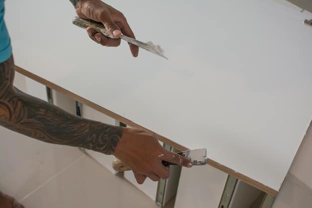 A person carefully applying joint compound to a drywall patch with a putty knife, ensuring a smooth and even surface.