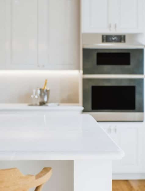A brightly lit kitchen with freshly painted cabinets, stainless steel appliances, and a clean countertop with minimal decor.