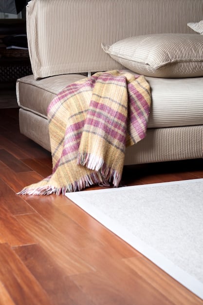 A cozy living room featuring a dark wood floor with a protective coating, showcasing throw rugs to protect high-traffic pathways.