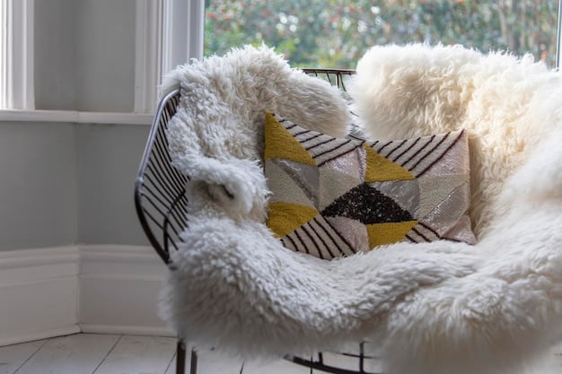 A close-up of a comfortable armchair with a plush cushion and a knitted blanket draped over the back. The armchair is positioned in front of a bookshelf filled with well-loved books, and a steaming mug of tea sits on a nearby side table.