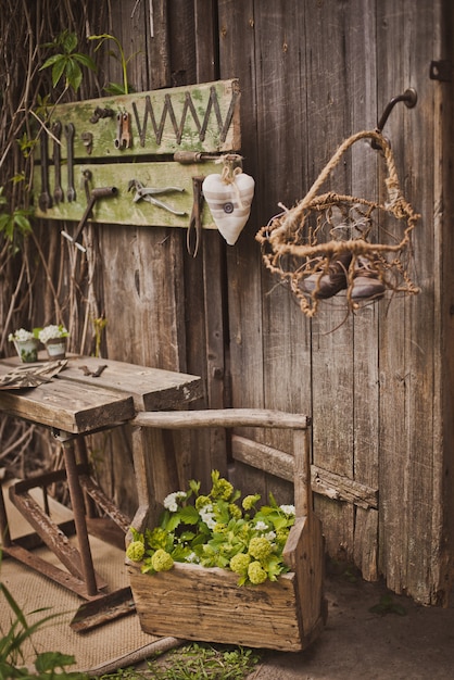 An outdoor dining area on a patio with a rustic wooden table, comfortable chairs, string lights, and potted herbs.