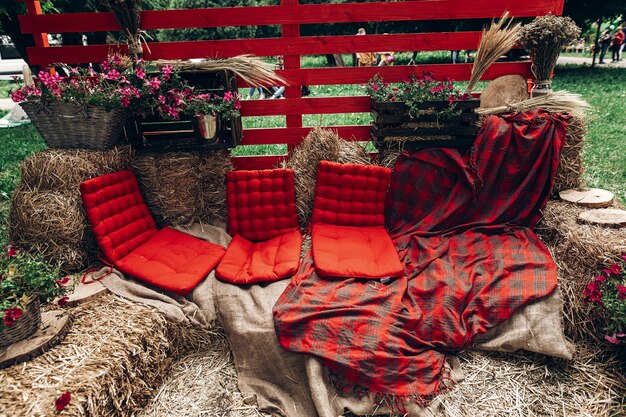 A cozy patio setup featuring a repurposed wooden pallet sofa with colorful cushions and a throw blanket. String lights are hung overhead, creating a warm and inviting atmosphere
