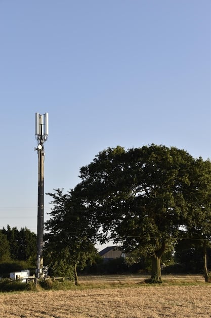 A close-up shot of a 5G cell tower in a rural setting, emphasizing the technological aspect. The tower is surrounded by green fields and a few scattered houses. The image highlights the advanced technology bringing connectivity.