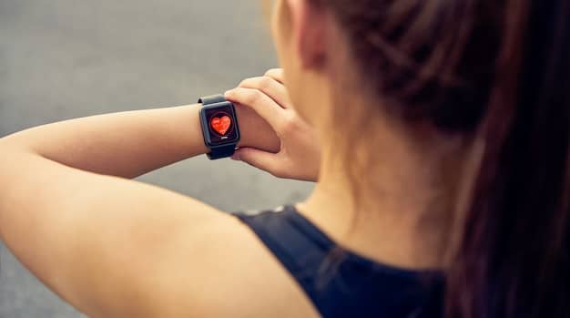 A detailed shot of the back of a smartwatch, showing multiple sensors (heart rate, SpO2, etc.) in contact with a person's wrist. The focus is on the technology and how it interacts with the body.