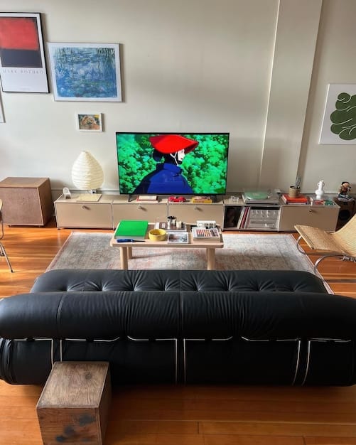 A comfortable living room with a large smart TV mounted on the wall displaying vibrant content, subtle smart light strips illuminating the back of the TV, and smart speakers discretely placed, creating an inviting entertainment space.